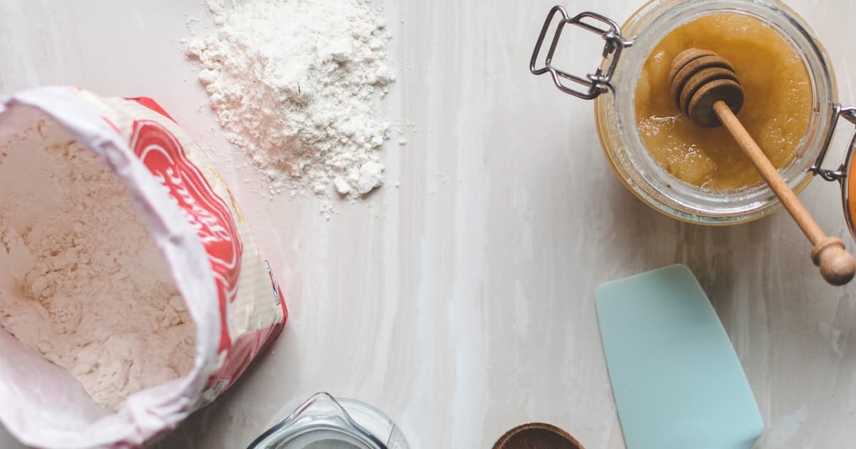 Flour, a honey jar, and measuring tools laid out on a light kitchen counter